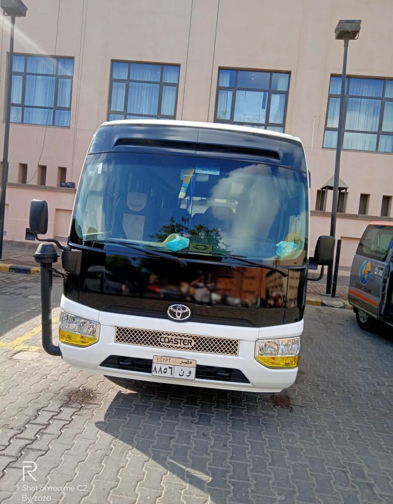 Air-conditioned tour transportation parked at an Egyptian historic site, offering convenient travel for tourists.